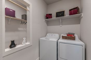 A laundry room with a washer and dryer and a cat figurine.